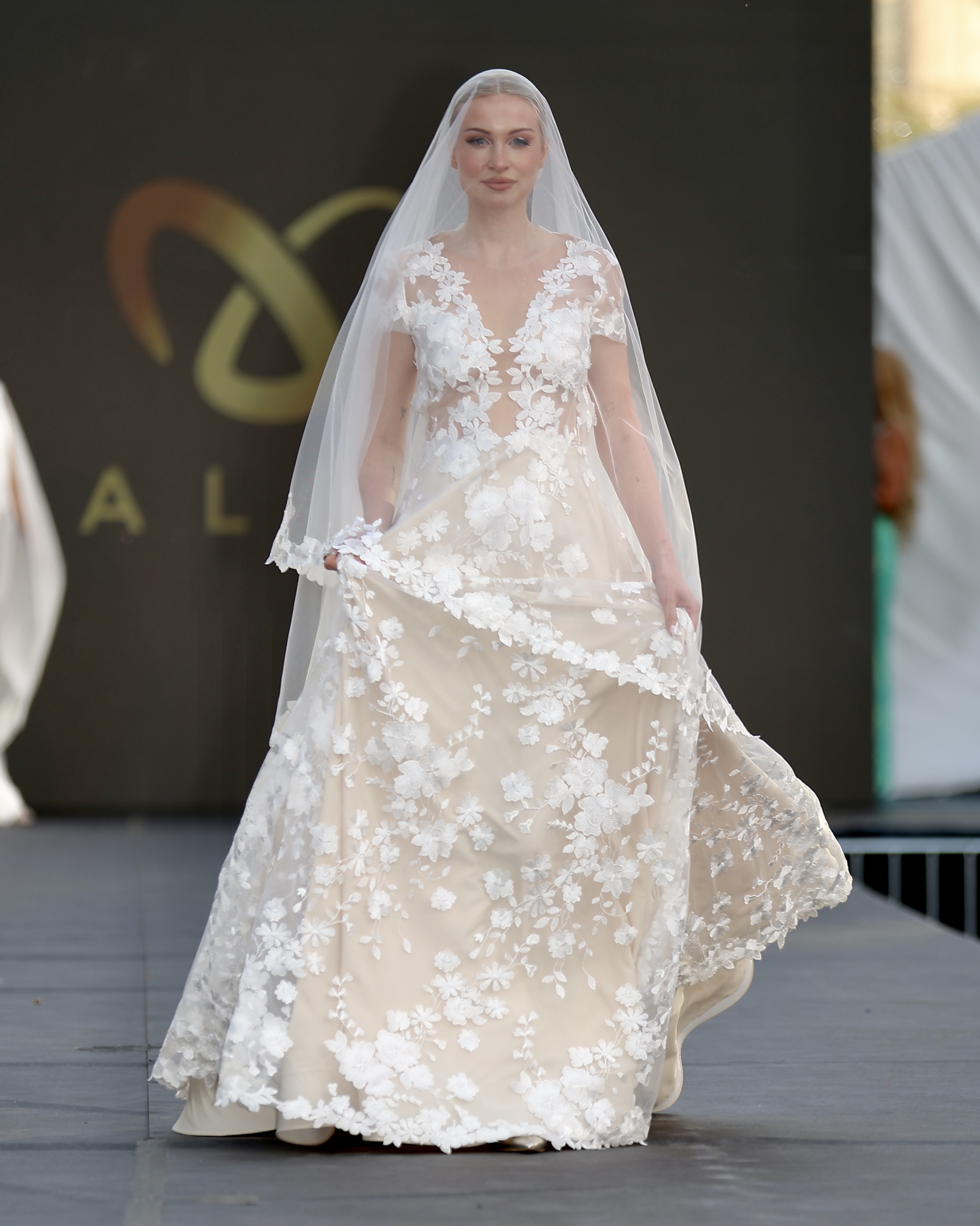 3D Blüten-Brautkleid NIKKA mit transparentem V-Ausschnitt und filigranen, handgesetzten Blüten-Spitzenmustern.